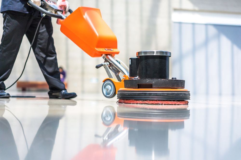 Person buffing floors with cleaning equipment, during the floor strip and wax process.